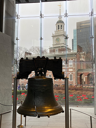 The Liberty Bell on display in the Liberty Bell Center, Philadelphia, with Independence Hall visible in the background